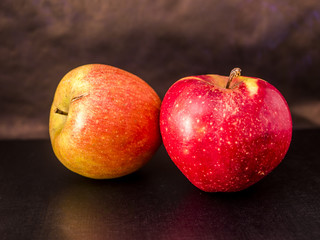 close up two apple fruits on the black surface