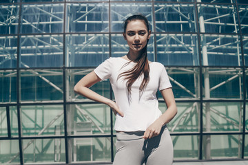 shapely active young girl in sports clothes trains outdoors, charged with power and motivation