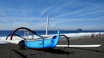 typisches balinesisches Fischerboot liegt auf schwarzem Lavasand am Meeresstrand