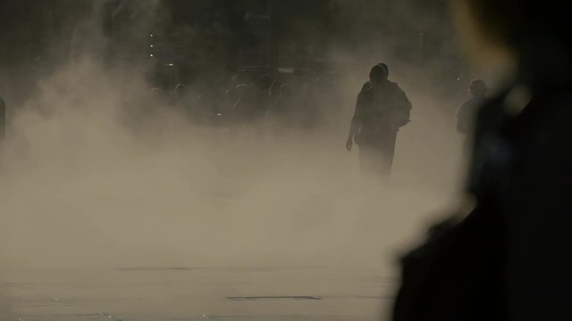 People walking through artificial smoke