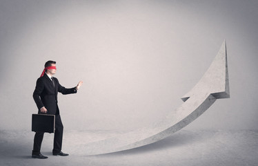 Obraz premium A scared blindfolded businessman forced to face a problem concept with illustrated arrow pointng to the sky in empty space.