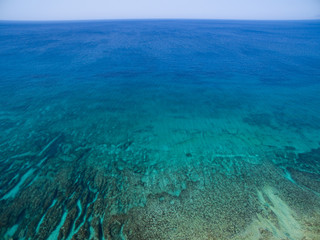 Aerial shot of tropical island turquoise sea waters with rock formations underneath