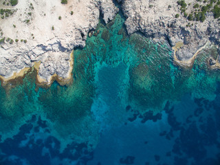 Birds eye view of transparent blue waters with coral reefs and cliffs on tropical island
