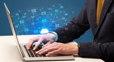 Businessman hand sending a bunch of messages on laptop with cloud computing concept
