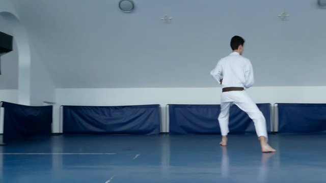 Young karateist practicing karate moves in the gym. Dolly gimbal 4K video.