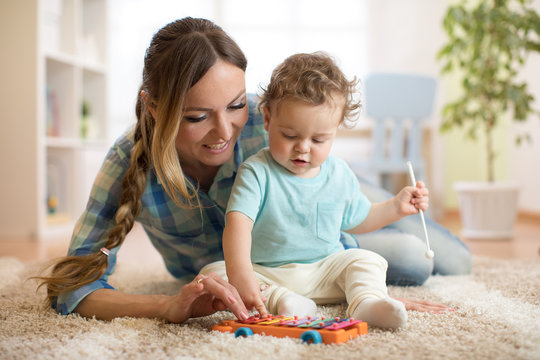 Mother is teaching child son how to play xylophone toy