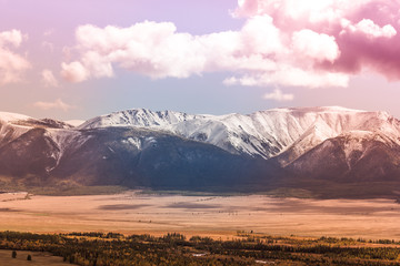 Snowy peaks of the mountain range under the pink sky. Mountain landscape in pastel color.
