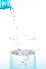Pouring water from bottle into glass on white background.