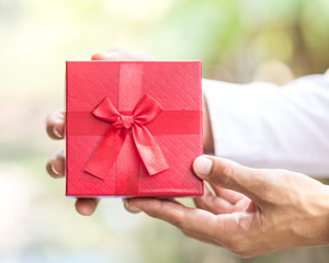 Business man hold red gift box in hands.