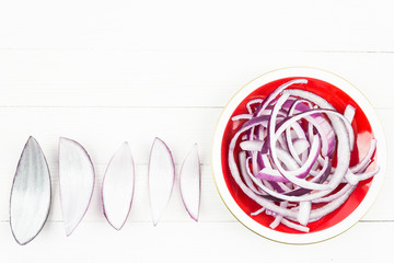 Slices of red fresh onion on a white table. Copy space for text