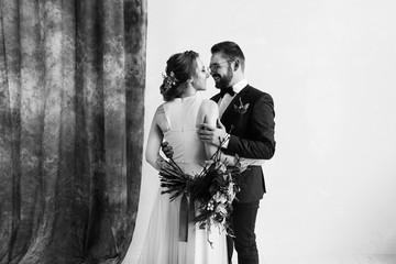 Wedding couple in studio. Black and white photo. Full-length portrait of pretty newlyweds with bouquet. isolated white background with copyspace