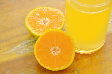 orange juice in glass and tangerine cutting on wooden board