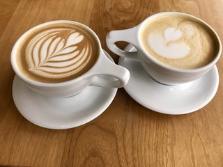Two romantic cups of chocolate mocha or caramel latte with  beautiful design in a cups of coffee  on a table in fancy  cafe in Portland Oregon USA