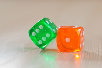 Colourful green and orange gambling dice on table
