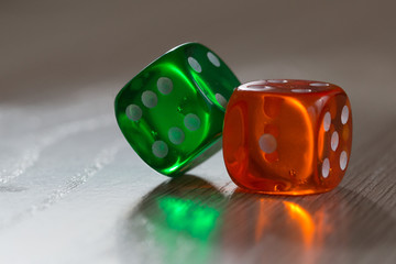 Colourful green and orange gambling dice on table