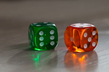 Colourful green and orange gambling dice on table