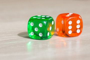 Colourful green and orange gambling dice on table
