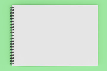 Blank white notebook with black spiral bound on green background