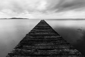 Long exposure first person view of a pier on Trasimeno lake (Umbria), with perfectly still water