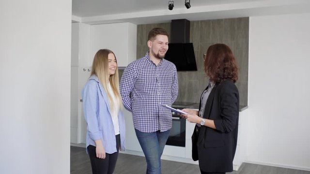 Man and woman interacting with realtor while watching the apartment for rent or buy
