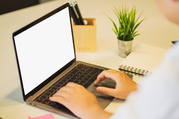 Man's hands using laptop with blank screen on desk.	