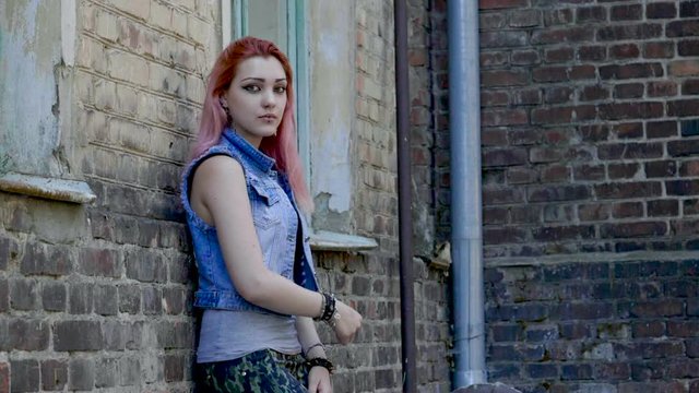 Attractive young teenage girl with pink hair looking at camera. Slow motion. HD