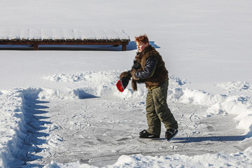 Fototapeta na wymiar boy skates in cold white winter on frozen lake