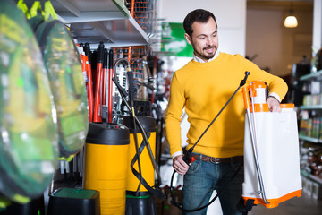 Smiling guy deciding on best garden sprayer