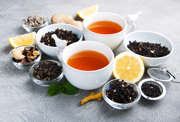 Cups of tea with aromatic dry tea in bowls