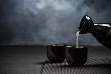 Tuinposter Pouring sake into sipping ceramic bowl © marcin jucha