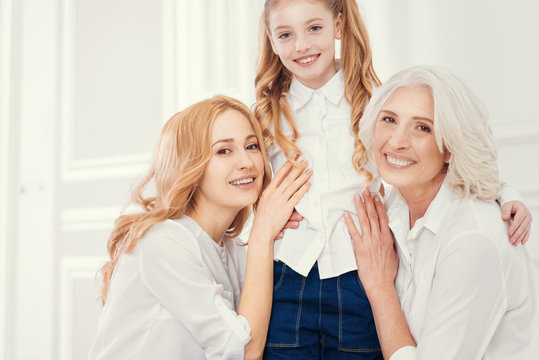 Like mother like daughter. Three beautiful ladies embracing and looking into the camera with cheerful smiles on their faces while spending a girly day together at home.