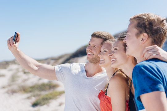 Group of young friends taking a beach selfie