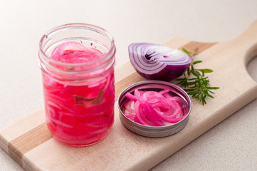 Obraz na płótnie Canvas Preserved pickled red onions. Pickling red onions is easy, simply marinate the onions in a brine with vinegar, salt and herbs. Pickled food can be preserved in glass jar for a very long time!