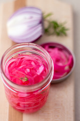 Obraz na płótnie Canvas Pickled red onions condiment. Pickling red onions is easy, simply marinate the onions in a brine with vinegar, salt and herbs. Pickled food can be preserved in glass jar for a very long time!
