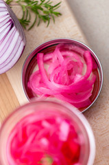 Obraz na płótnie Canvas Red onions pickled from above. Pickling red onions is easy, simply marinate the onions in a brine with vinegar, salt and herbs. Pickled food can be preserved in glass jar for a very long time!