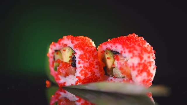 Sushi rolls rotated over black background. Sushi roll set with tuna, vegetables and flying fish roe closeup. 4K UHD video footage. 3840X2160