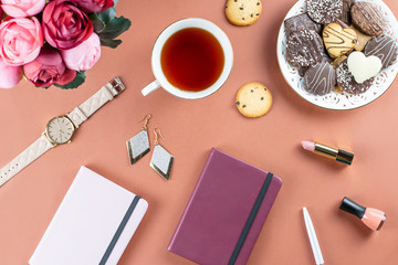 Flat lay home office desk. Feminine workspace with diary, flowers, sweets, fashion accessories. Fashion blogger concept.