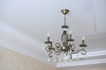 Beautiful iron chandelier of bronze color. The forged chandelier on the ceiling