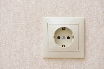 Electrical socket in beige color built into the wall. Outlet