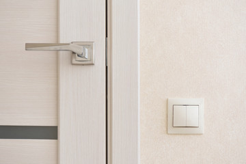 Beige light switch installed next to the door on the wall