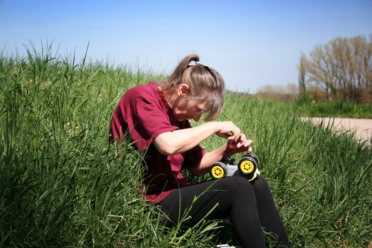 Eine Gro&szlig;mutter repariert ein Spielzeugauto im Gras