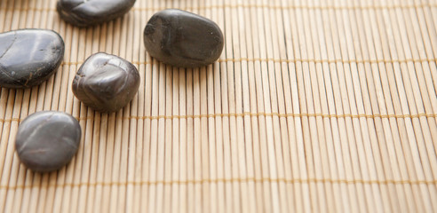 Fototapeta na wymiar galets sombre sur fond de bambou