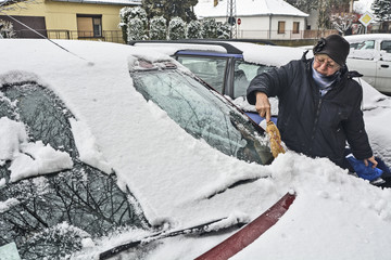 Driver cleaning snow from the windshield