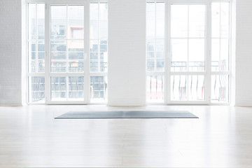Fototapeta Gym white interior with black yoga mat, big windows, no people. Copy space obraz