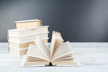 Open books on wooden table, black board background. Back to school. Education business concept.