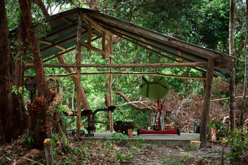 Fototapeta na wymiar Amateur wooden open air gym in the middle of the jungle with exercise bike, press bench and dumb bells. Cambodia, Koh Rong Sanloem Island. 