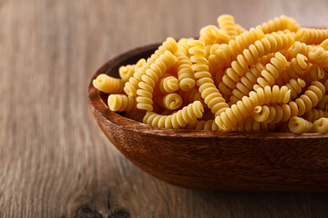 Italian raw pasta fusilli on wooden background