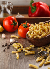 Italian raw pasta fusilli on the background of other ingredients for cooking