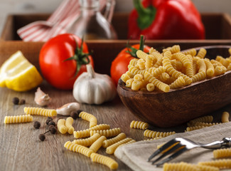 Italian raw pasta fusilli on the background of other ingredients for cooking