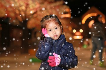 Portrait of little girl touching her cheek in snow, Winter time.